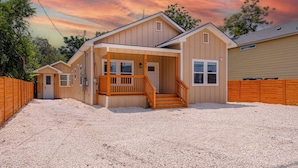 A two-story house with a covered porch and a staircase leading to the entrance. - Generous 4br/3ba Charmer Near Glorius Downtown! (San Antonio)