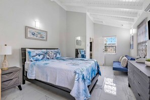 A bedroom with a bed, bedside table, dresser, and a window.