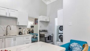 Eine kleine Küche mit weißen Schränken, einer Marmorarbeitsplatte und einem blauen Sofa.