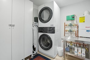 A laundry room with two stacked front-loading washing machines, a water heater, and various plumbing fixtures. - Luxury Scandinavian nature escape, private saun (Springfield)