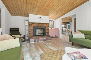 A living room with a fireplace, a green sofa, a brown leather chair, and a white coffee table.