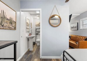 A modern bathroom with a sink, toilet, and mirror. There is a wooden table and a brown leather sofa in the room. - Vibrant Cowgirl Hideaway - Rodeo Themed, Fire Pit & 1/2 mile walk to Whiskey Row (Prescott)