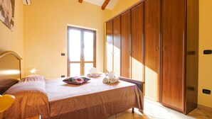 A hotel room with a bed, a wooden wardrobe, a window, and a wall-mounted air conditioner. - Gorgeous home in Perdifumo with WiFi (Perdifumo)