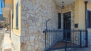 A building with a stone facade, a metal gate, and a door leading to a staircase. - 1 bedroom amazing apartment in Acquedolci (Acquedolci)