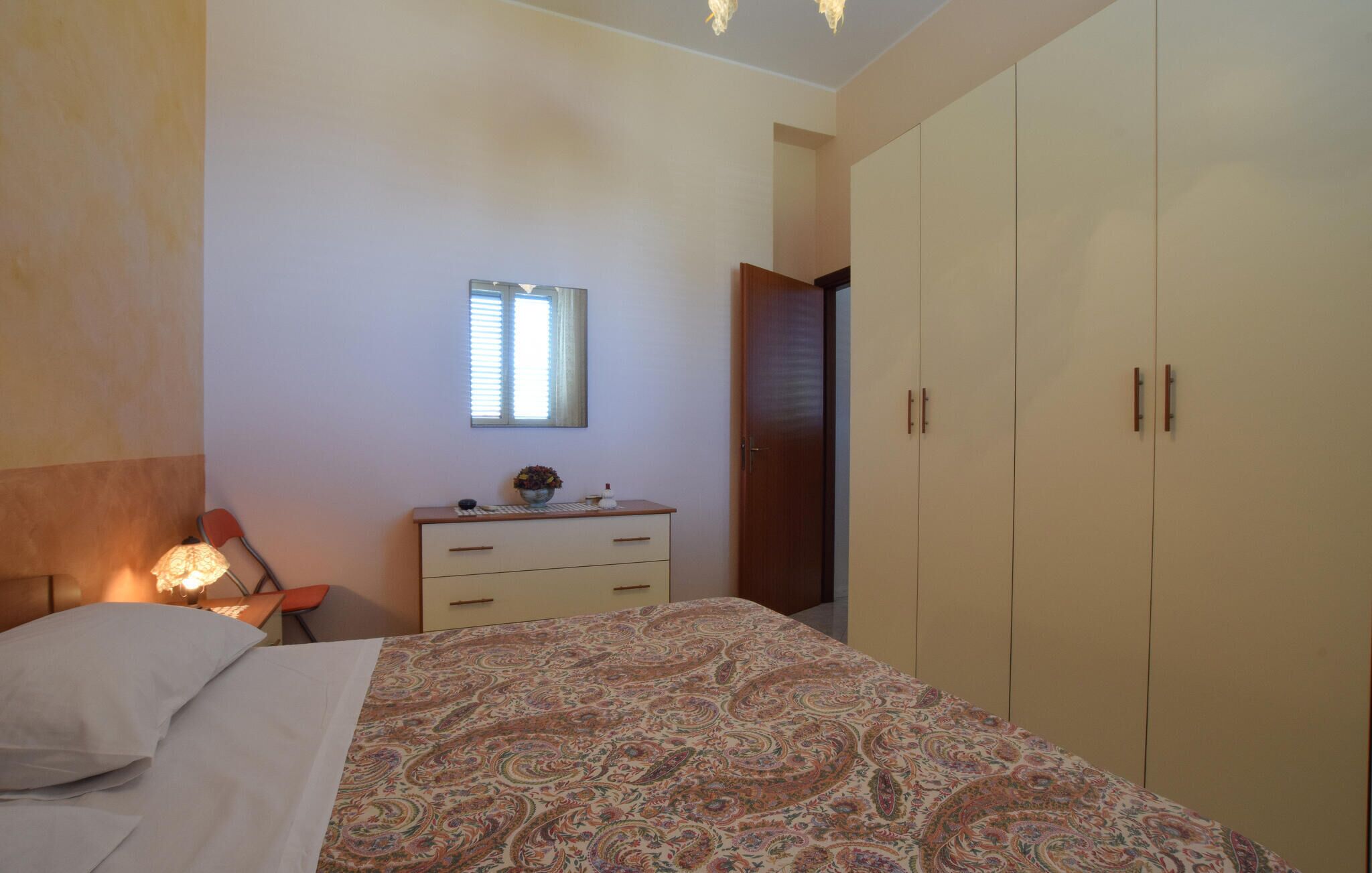 A bedroom with a bed, a dresser, a mirror, and a wardrobe.