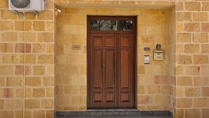 Una porta doble de fusta amb una placa de número, una closca de correu i una unitat de aire condicionat penjada a la paret.