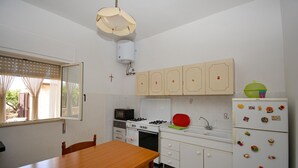 A compact kitchen with white cabinets, a stove, a microwave, and a refrigerator. - 2 bedroom pet friendly home in Comiso (Comiso)