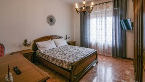 Un dormitorio con cama de madera, candelabro, televisor en la pared y un adorno de sol.