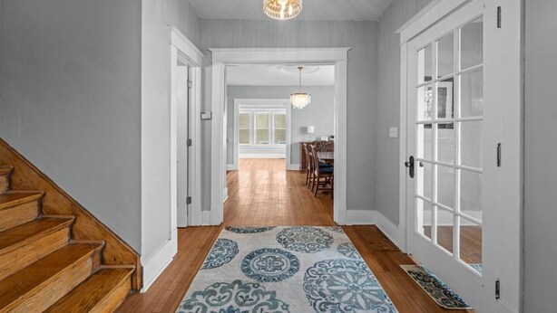 A hallway with a wooden staircase, a patterned rug, and a chandelier. - Arcade Games, Pool Table, Huge Deck, Seasonal View (Davenport)