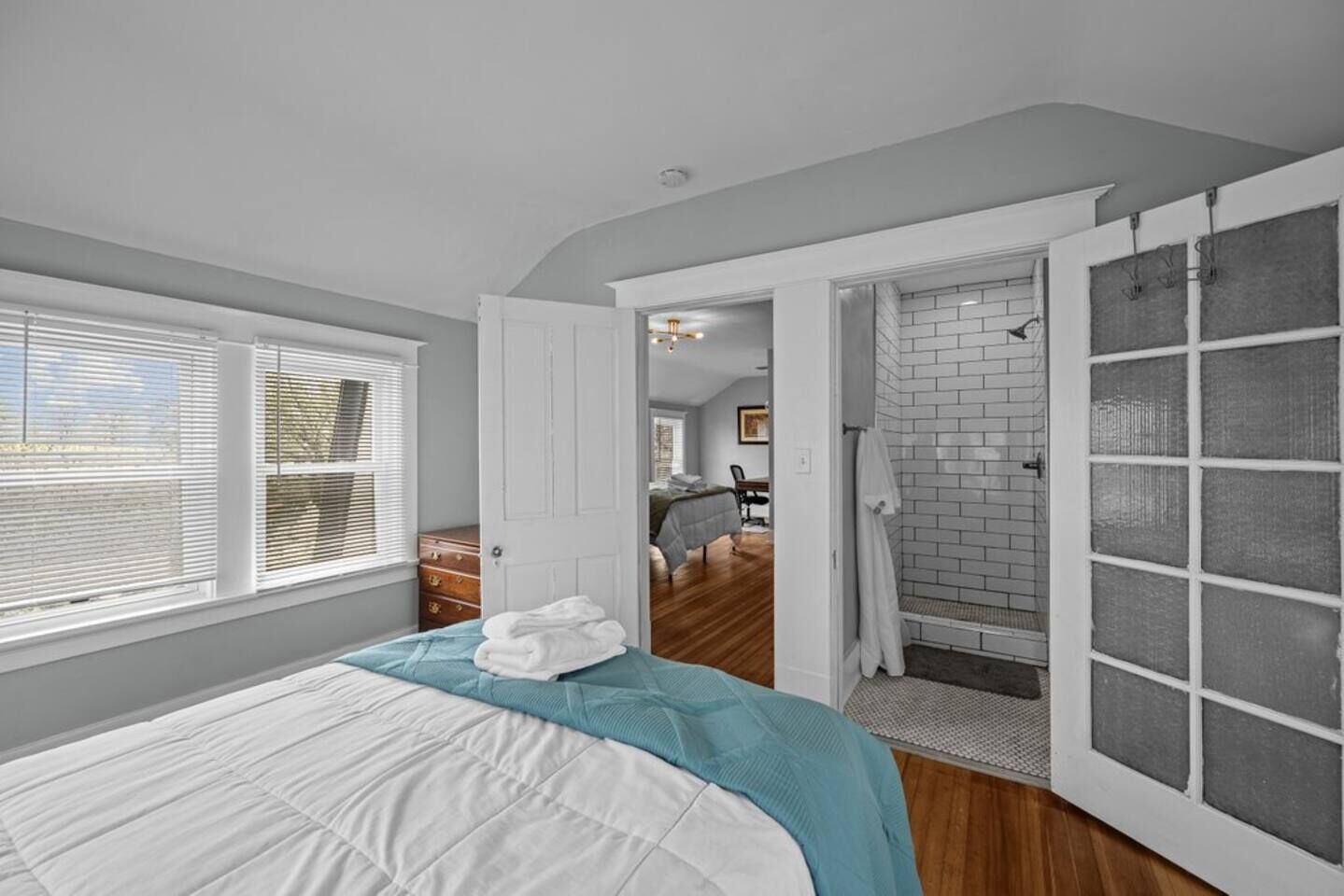 Une chambre à coucher avec un lit, une porte donnant sur une salle de bain et une vue sur une autre pièce.