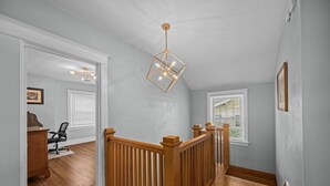 A spacious hallway with wooden flooring, a wooden railing, and a geometric pendant light. - Arcade Games, Pool Table, Huge Deck, Seasonal View (Davenport)