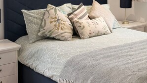 A bedroom with a bed, pillows, a nightstand, a lamp, and abstract wall art. - Cosy Adorable 1 Bedroom Studio in London (London)