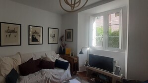 A living room with a sofa, a TV, and framed pictures on the wall. - Impressive nature, cultural life and sports near Madrid: El Escorial (San Lorenzo de El Escorial)