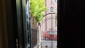 A doorway leading to a gated area with a red car parked outside. - Impressive nature, cultural life and sports near Madrid: El Escorial (San Lorenzo de El Escorial)