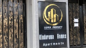 Ein Schild für 'Kinderuma Homes Apartments' mit einem Logo mit einem stilisierten Gebäude.