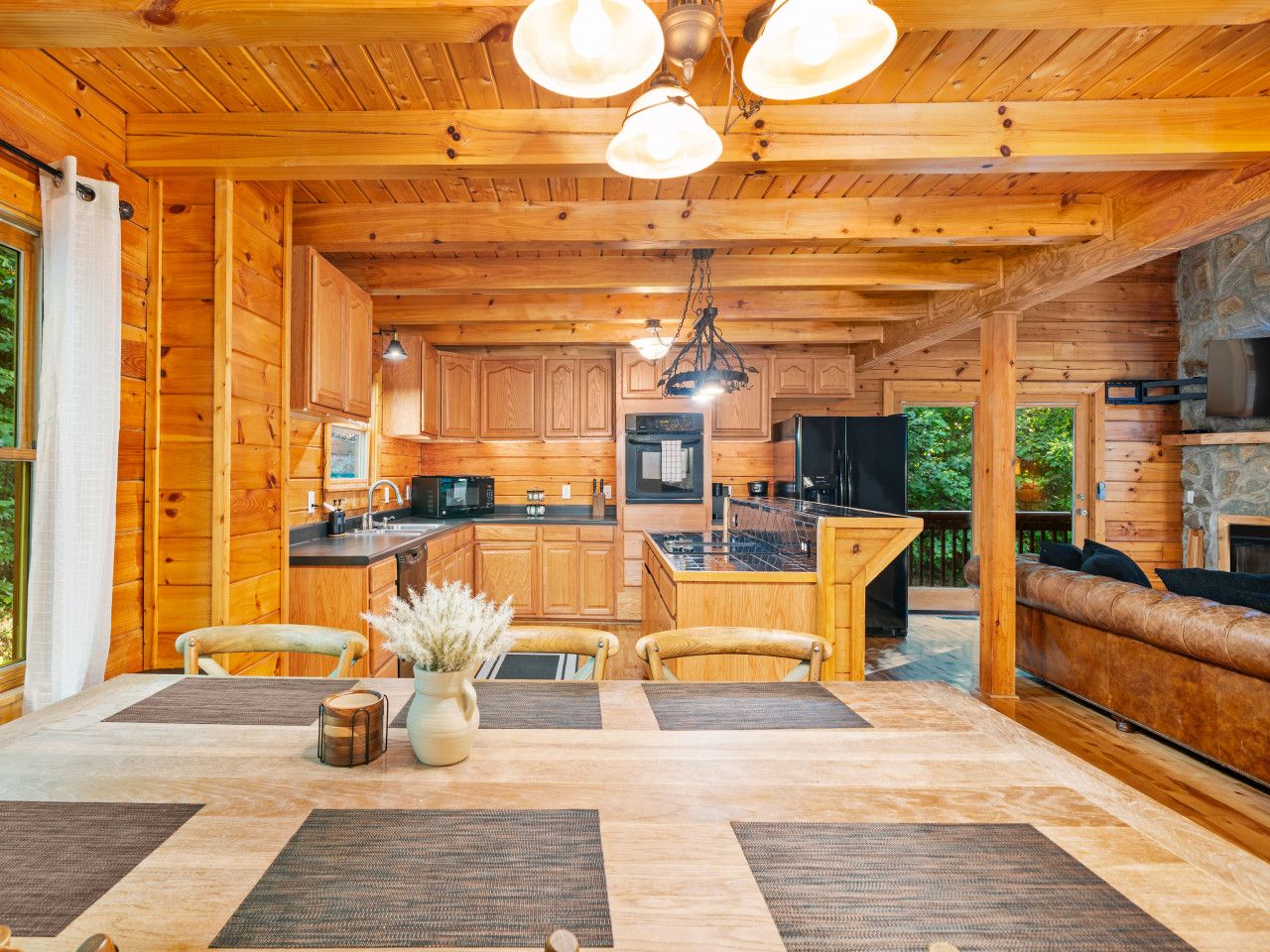 Interior de una cabaña de madera con cocina, comedor y chimenea de piedra.