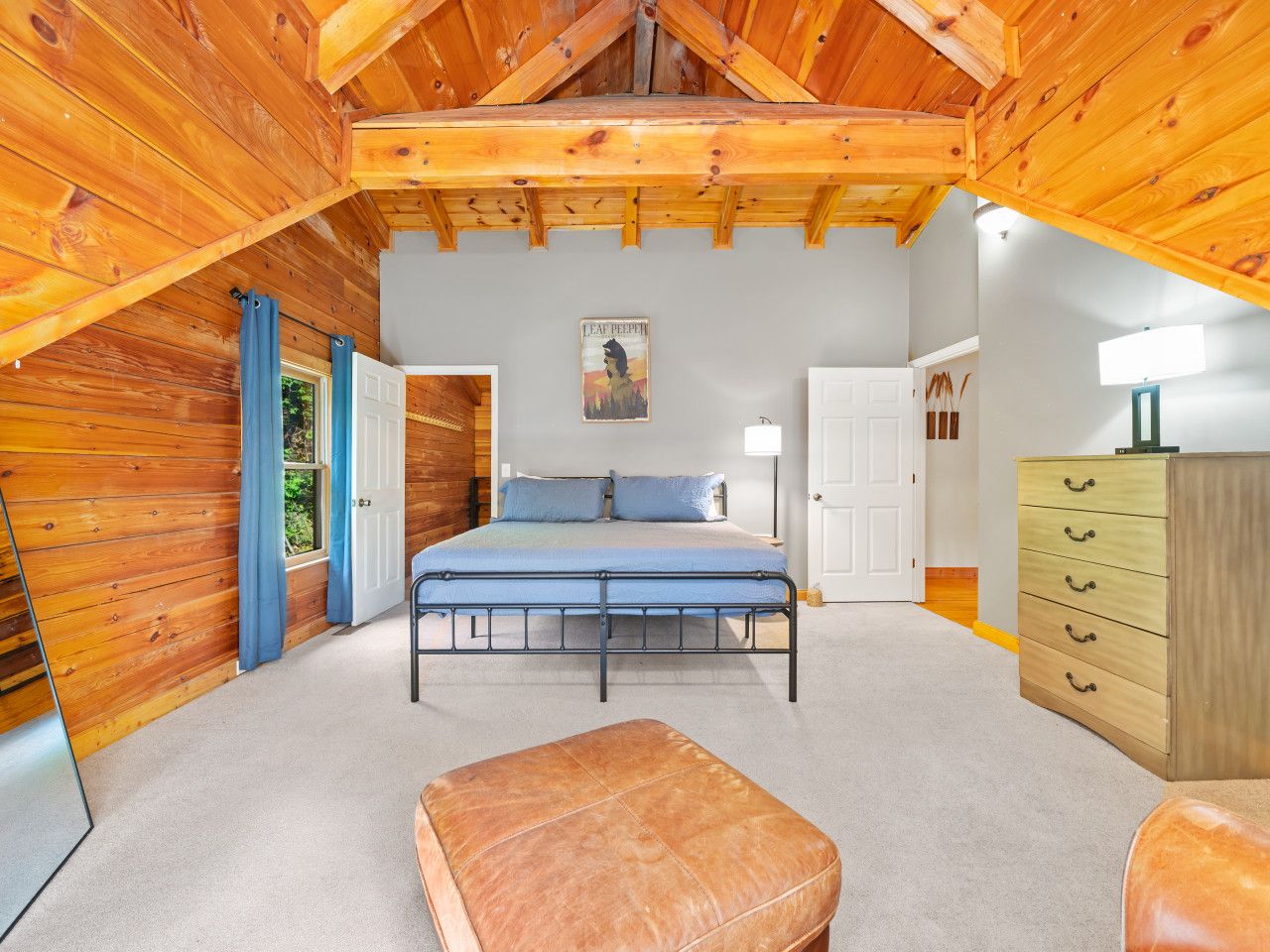 Un dormitorio con cama, cómoda, silla y ventana con cortinas.