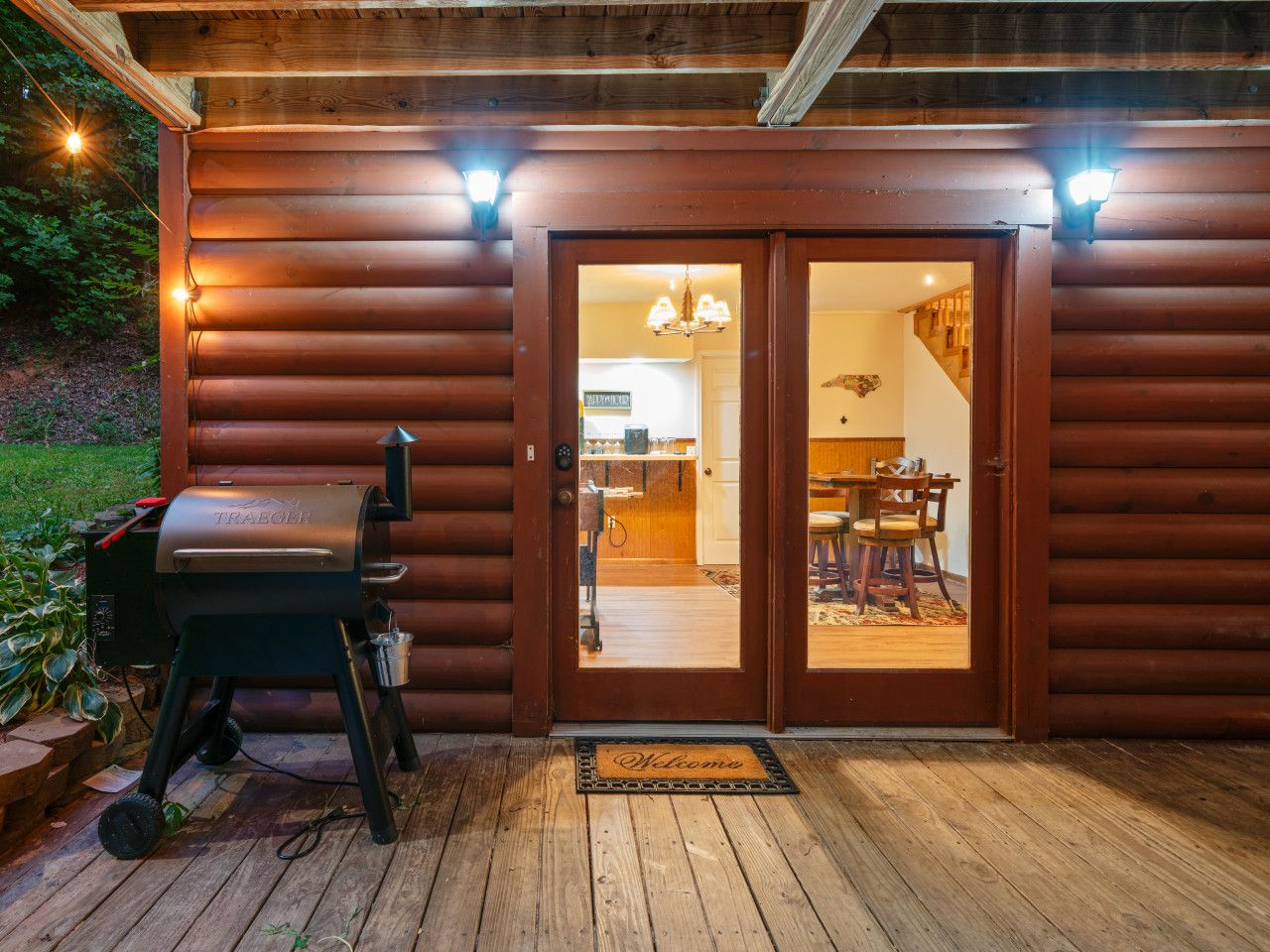 Une cabane en bois avec un barbecue à l’extérieur, un coin repas à l’intérieur et un escalier menant à l’étage supérieur.