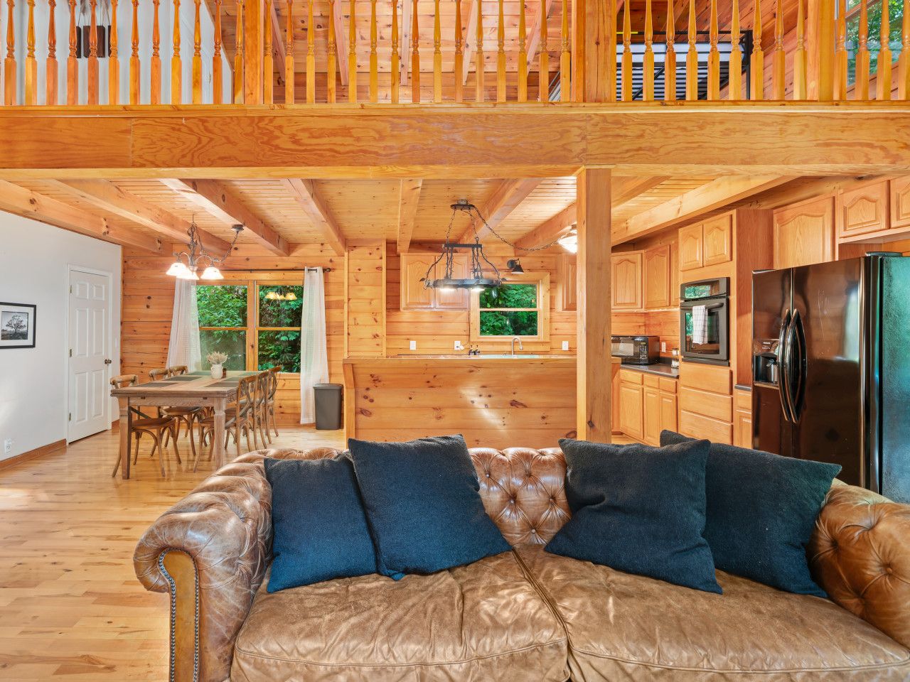 A spacious wooden cabin with a dining area, a living room with a leather couch, and a kitchen with modern appliances.