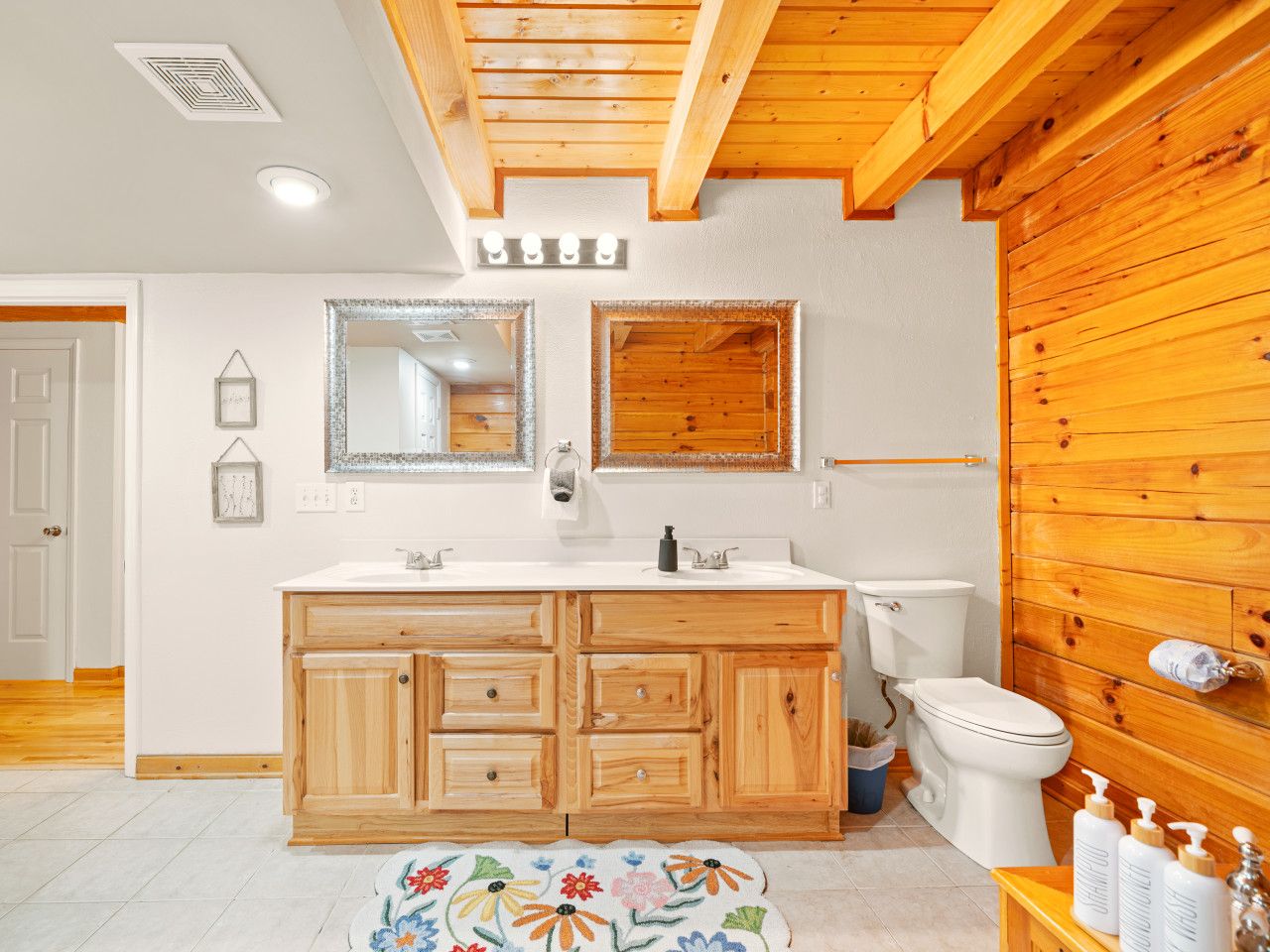 A bathroom with wooden cabinets, a white sink, two mirrors, a toilet, and a shower area.