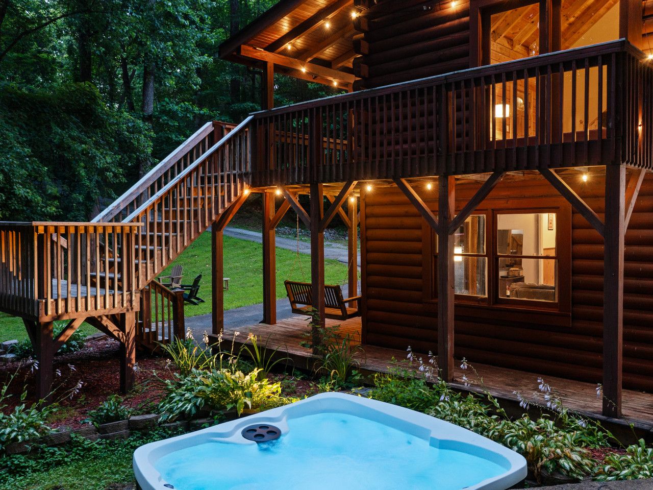 A wooden cabin with a hot tub, deck, and outdoor seating area.
