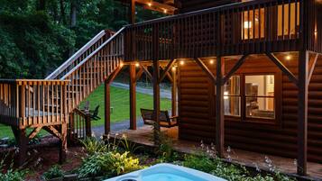 A wooden cabin with a hot tub, deck, and outdoor seating area.