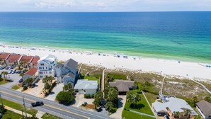 A coastal hotel with multiple buildings, a beach with umbrellas, and a road leading to the beach.