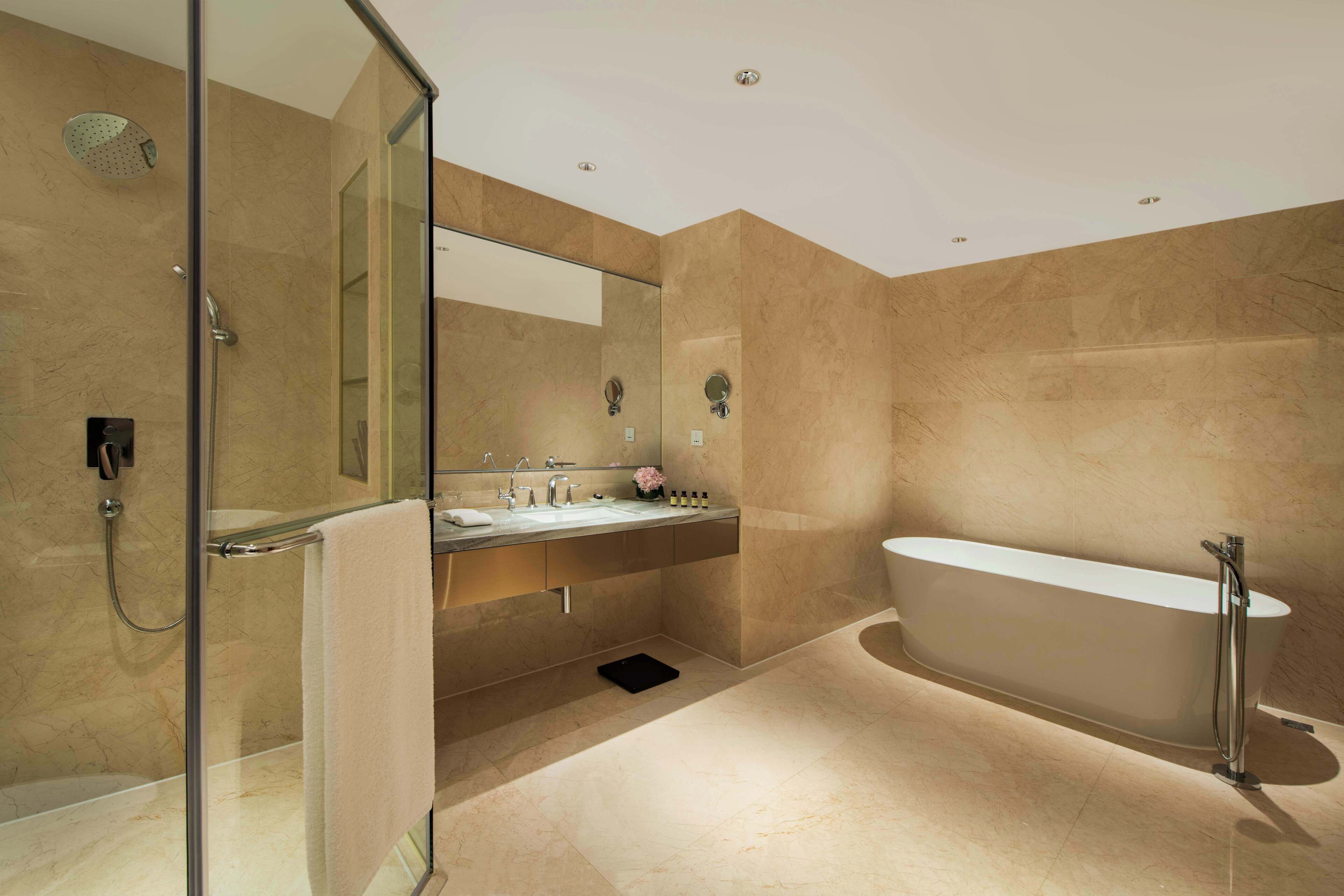 A modern bathroom with a glass-enclosed shower, a freestanding bathtub, and a vanity with a mirror and sink.