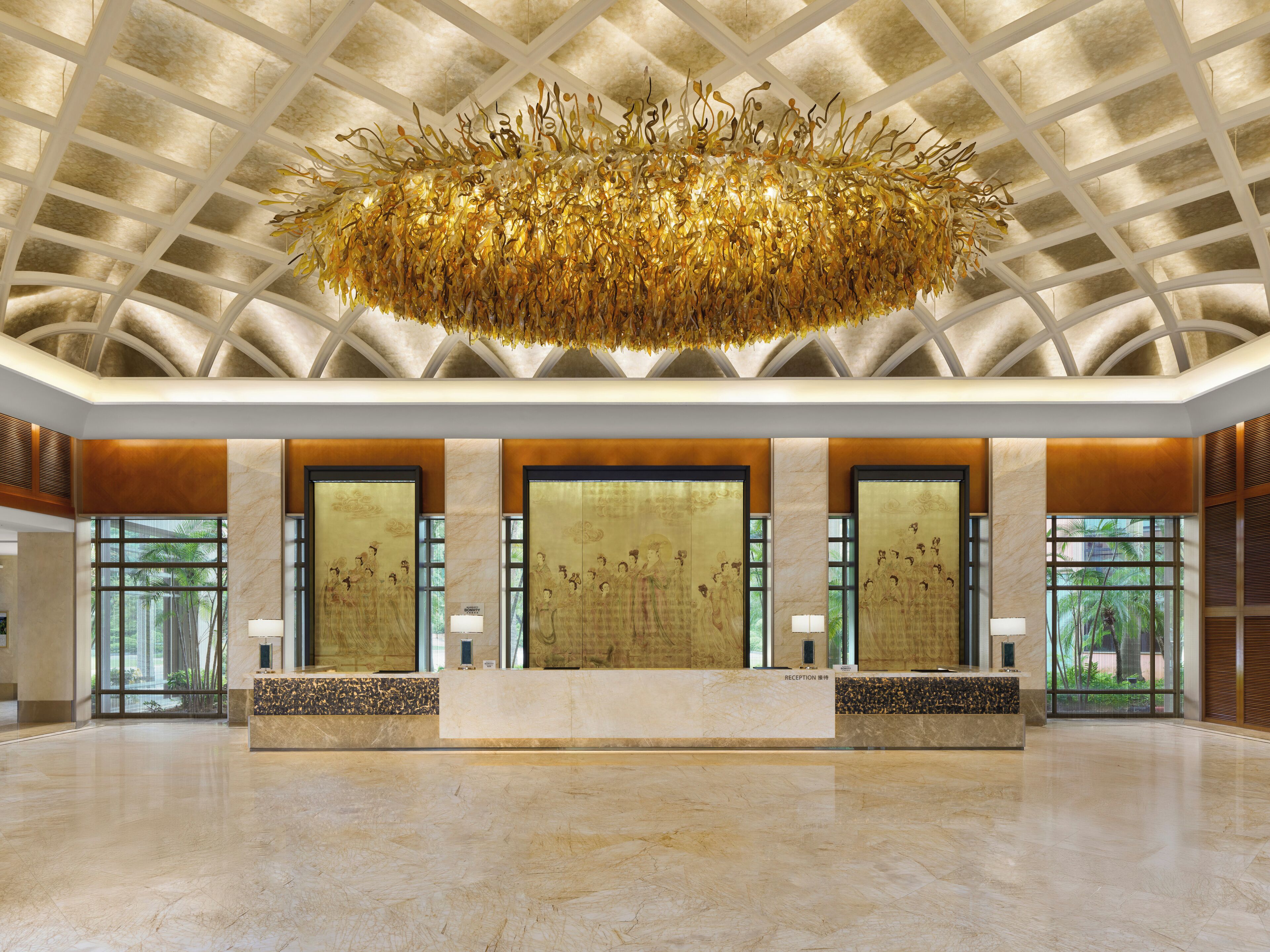 A spacious lobby with a high ceiling, a central reception desk, and large windows allowing natural light.