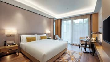 A modern hotel room with a large bed, bedside tables, a desk with a chair, and a television.