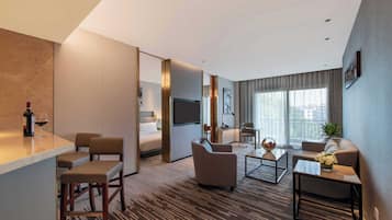 A modern hotel room with a living area, a dining area, and a bedroom.