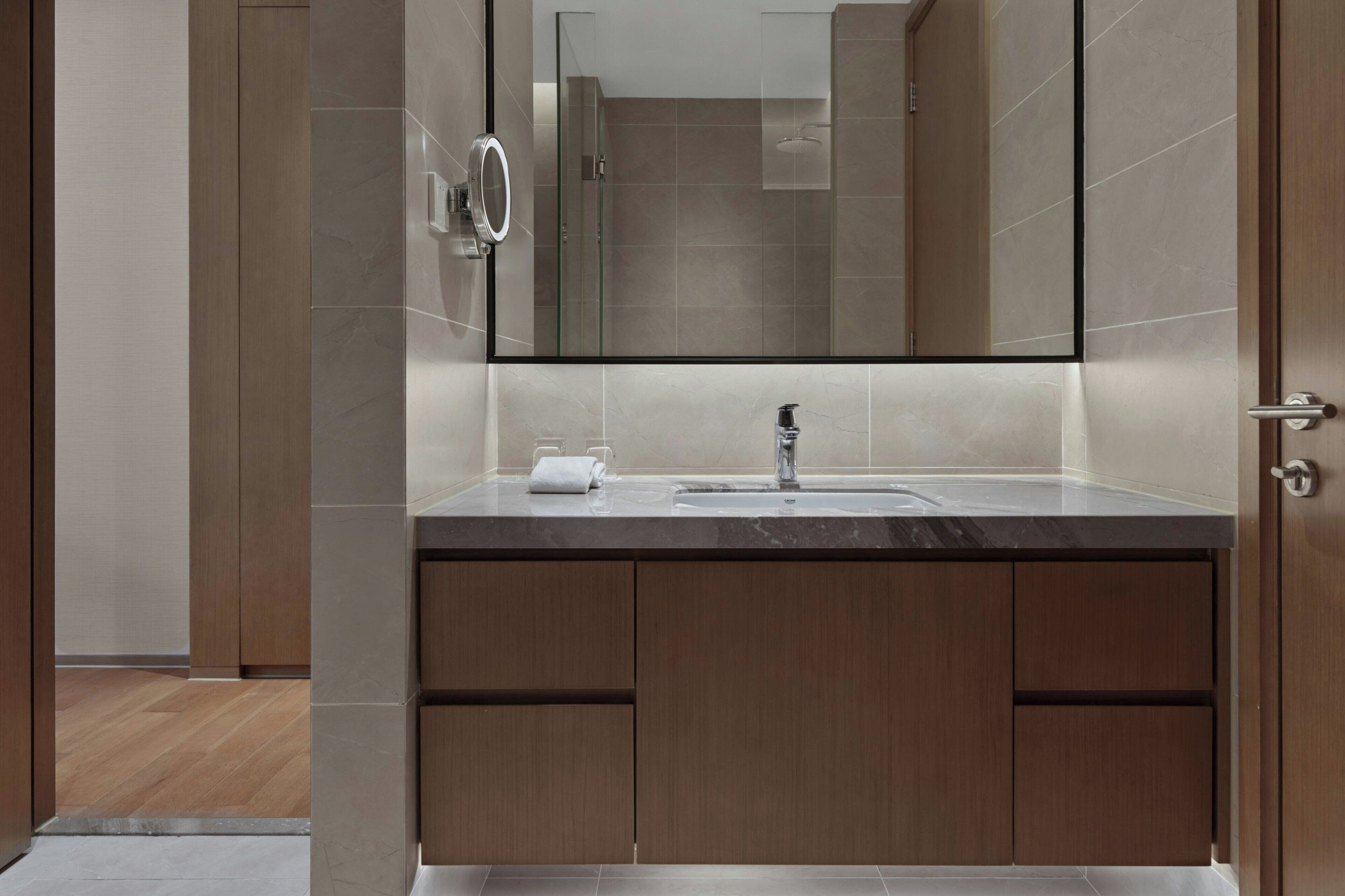 Un baño moderno con un espejo grande, un lavamanos y armarios de madera.