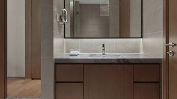 A modern bathroom with a large mirror, a sink, and wooden cabinets.