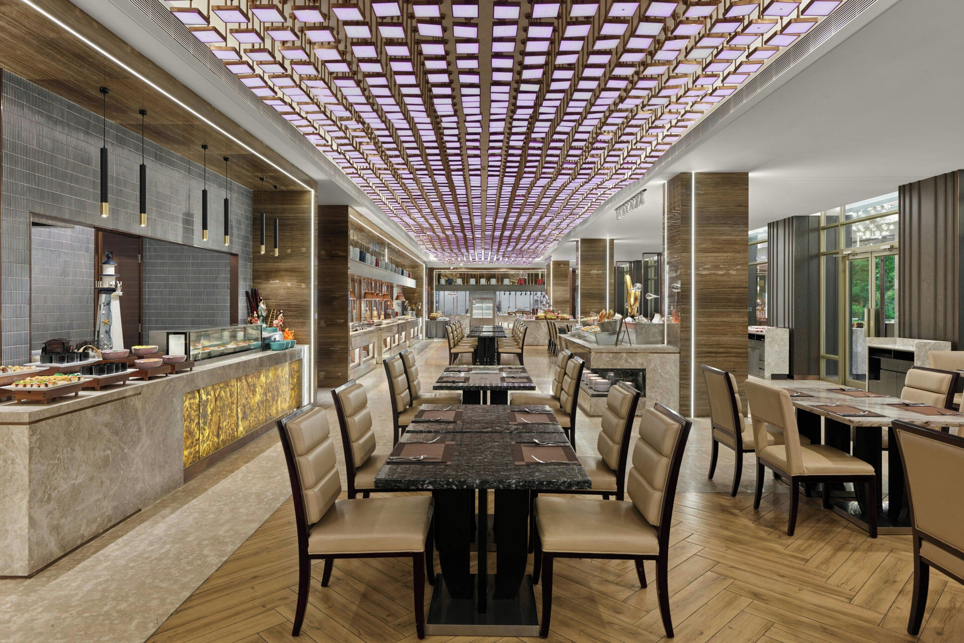 A modern restaurant with a central bar area, multiple dining tables, and a unique ceiling design.