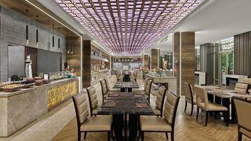 En moderne restaurant med et centralt barområde, flere spiseborde og et unikt loftdesign.