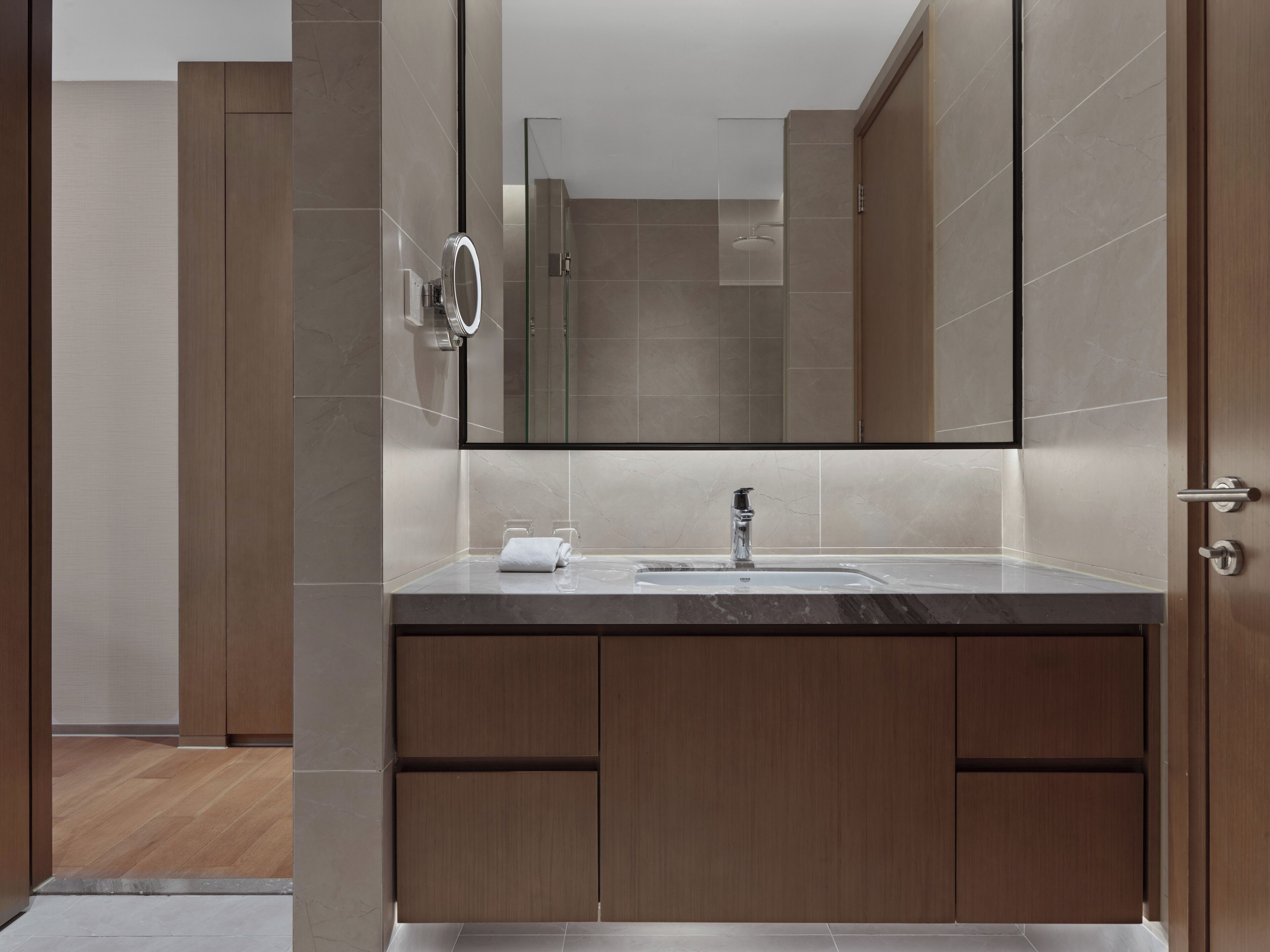 A modern bathroom with a large mirror, a sink, and a glass shower enclosure.