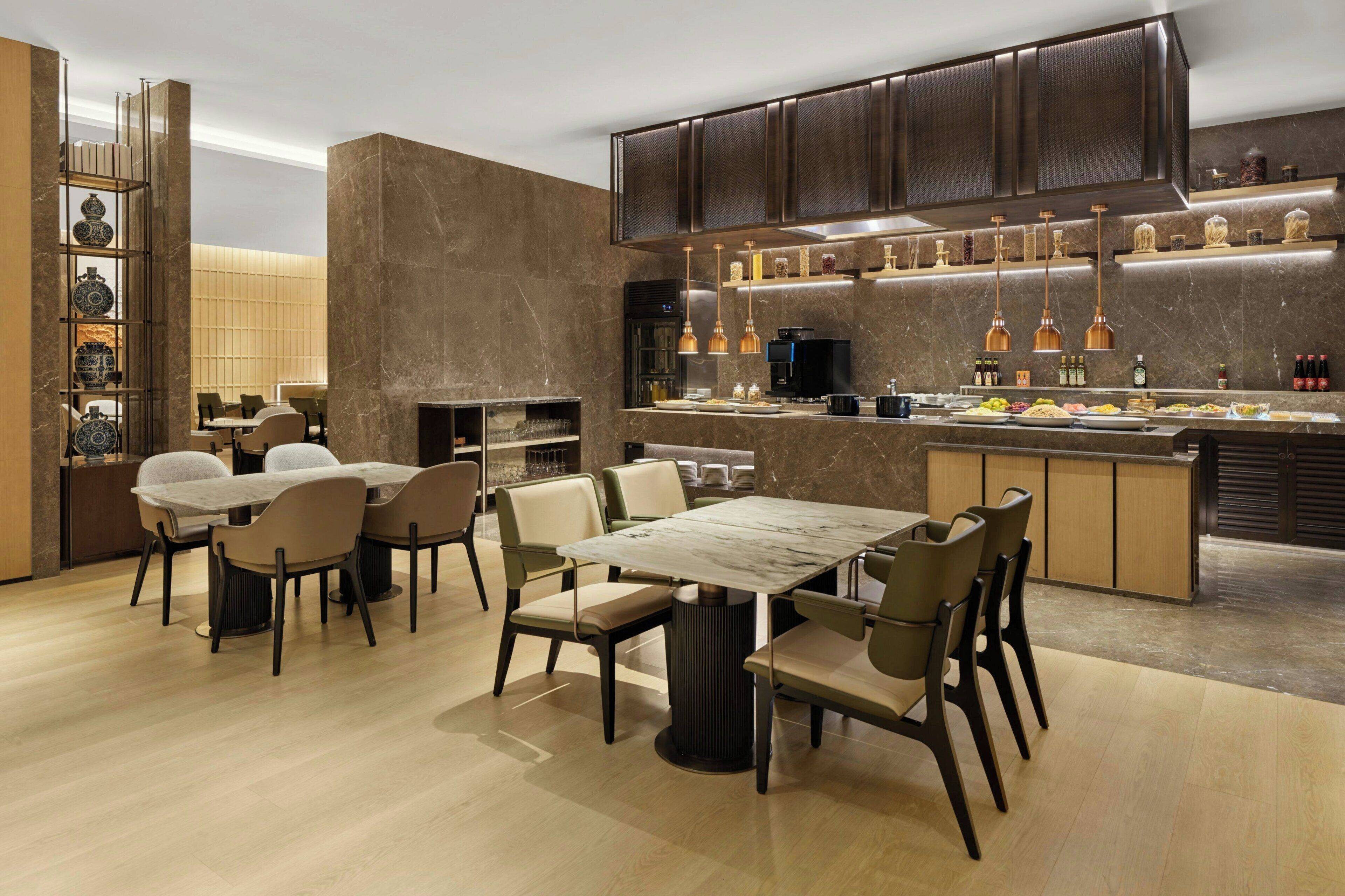 A modern kitchen with a central island, built-in appliances, and pendant lighting.