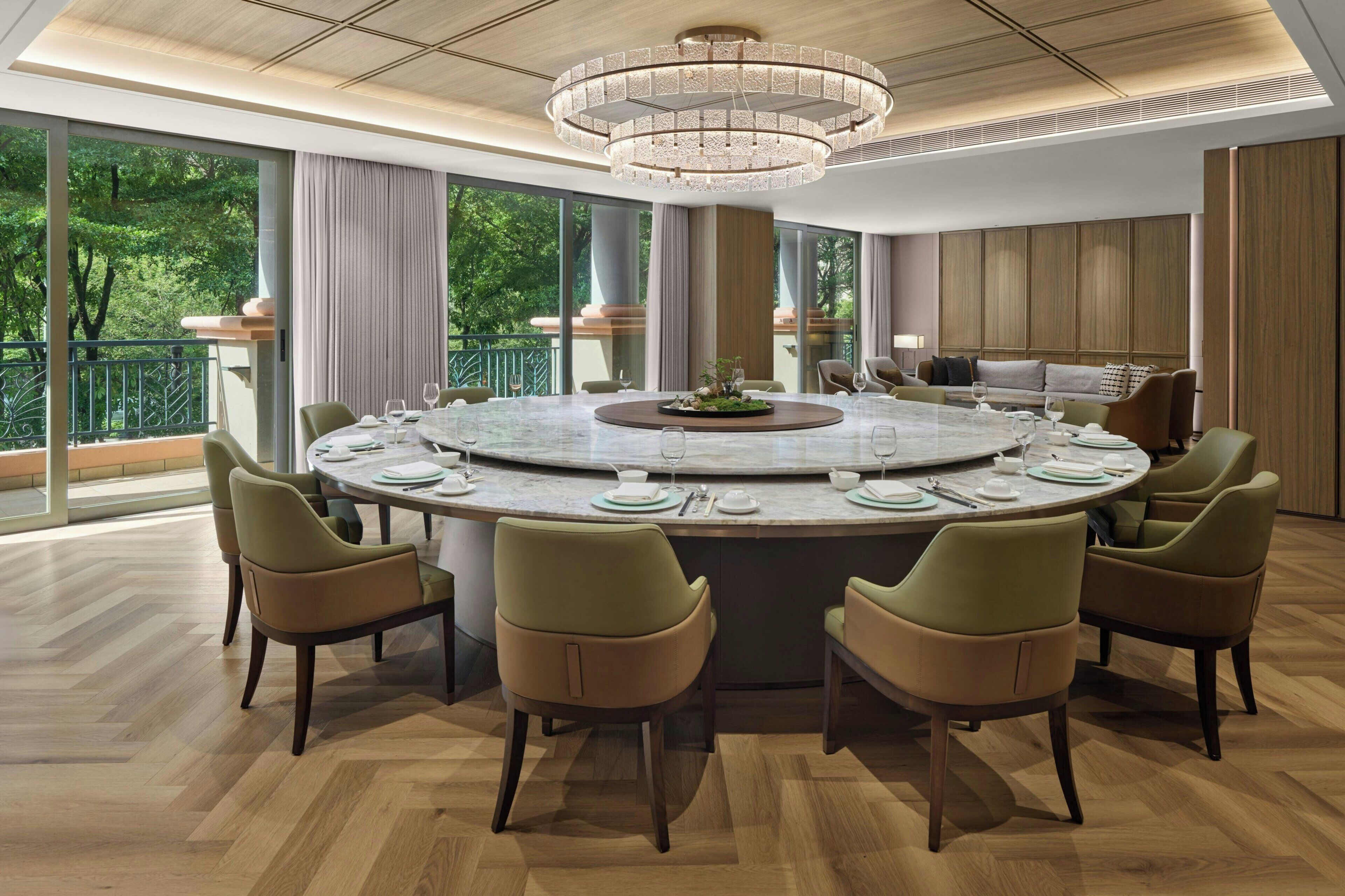 A modern dining area with a round table, six chairs, and a chandelier.