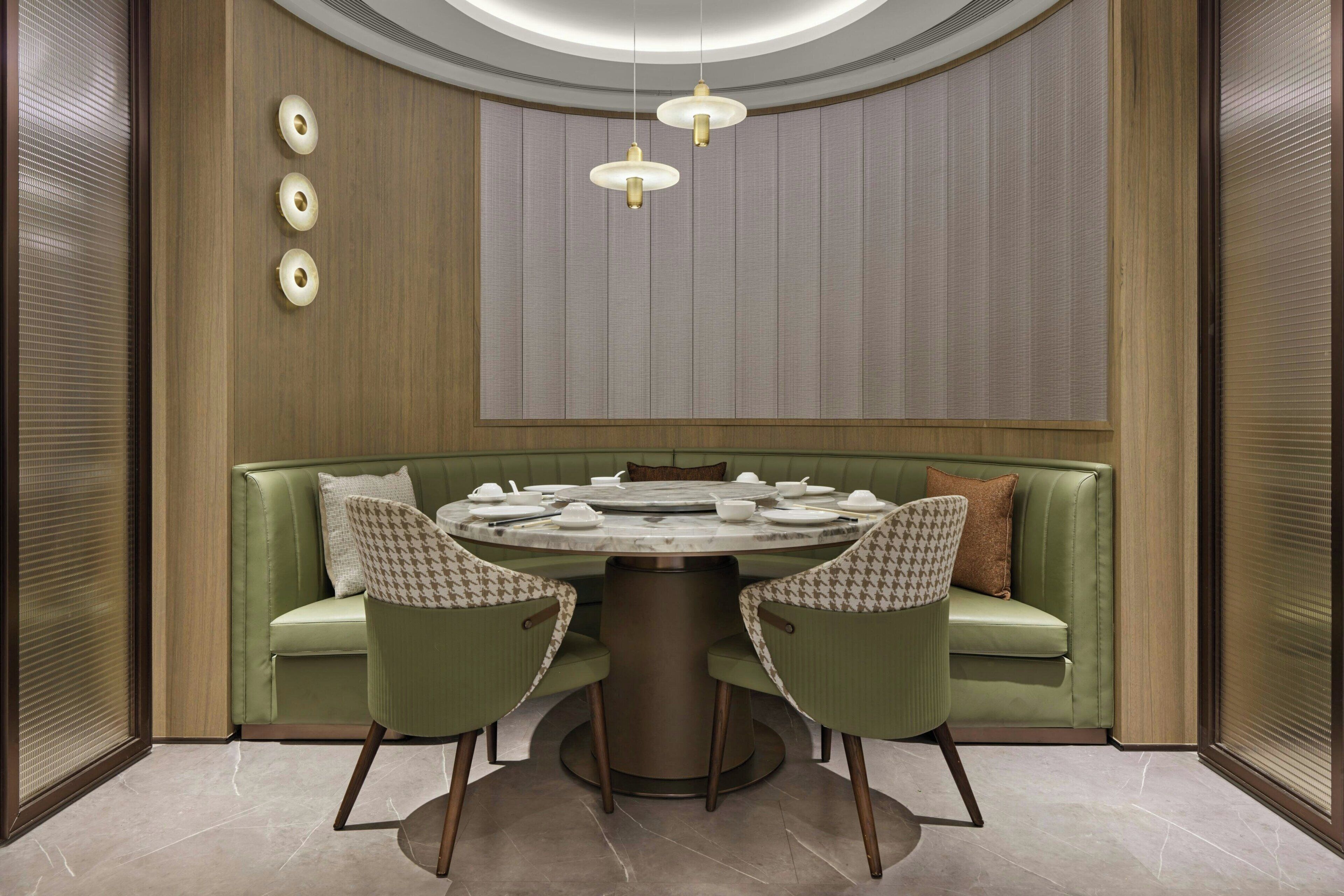 Un comedor con una mesa redonda, dos sillas, un sofá verde y una lámpara en el techo.