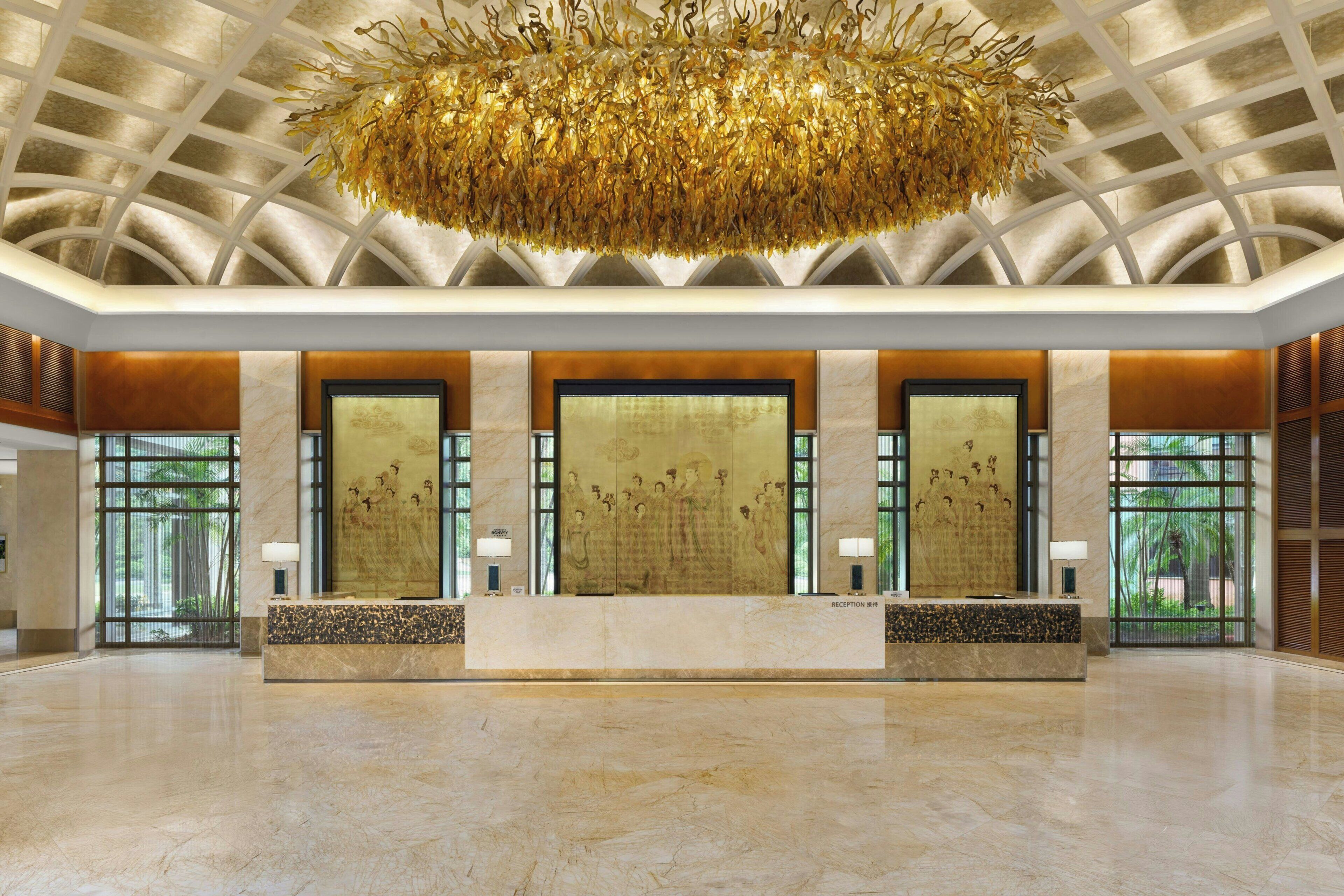 A spacious lobby with a high ceiling, a central reception desk, and large windows allowing natural light.