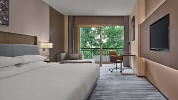 Une chambre d’hôtel avec un grand lit, un bureau, une chaise et un téléviseur.