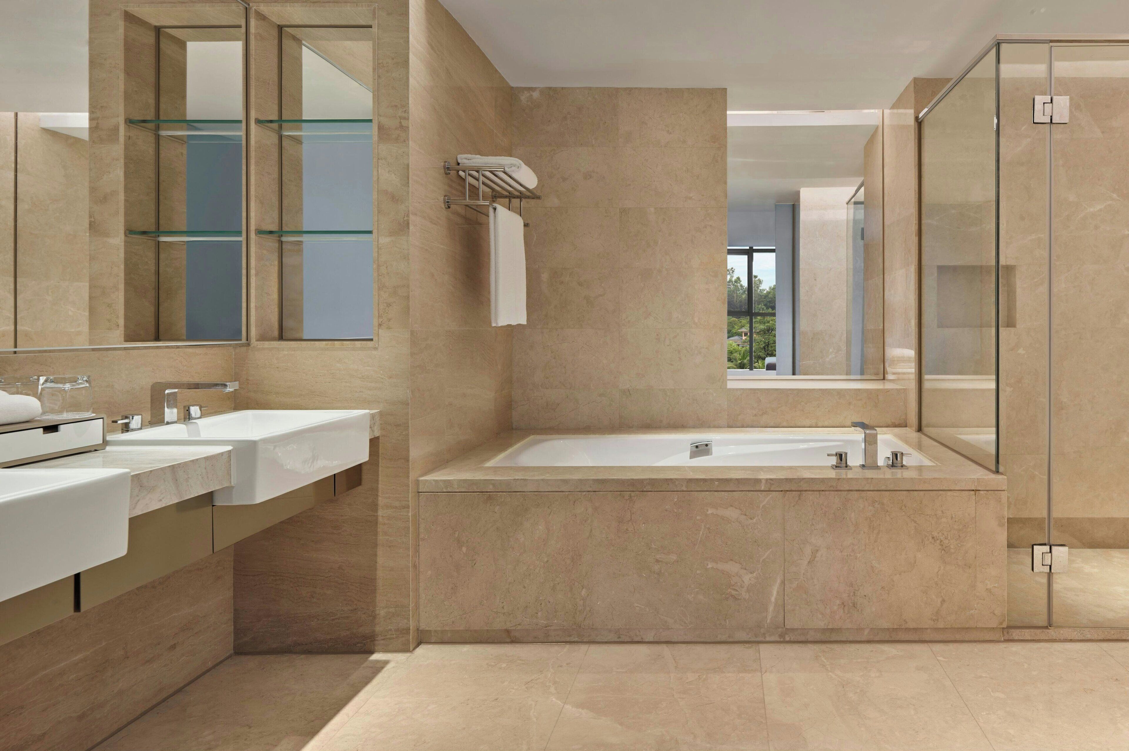 Un baño moderno con una bañera grande, dos lavamanos y una cabina de ducha de vidrio.