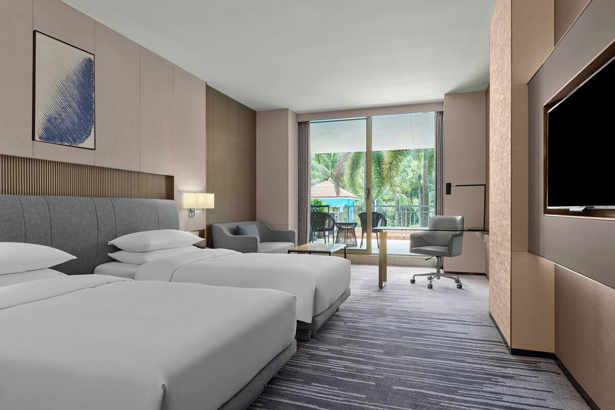 Ein Hotelzimmer mit zwei Betten, einem Schreibtisch, einem Stuhl und einem Fernseher.