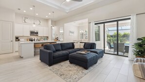 Una sala de estar moderna con un sofá modular, un comedor y una cocina.