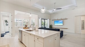 Una cocina moderna con una isla grande, luces colgantes y un ventilador de techo.