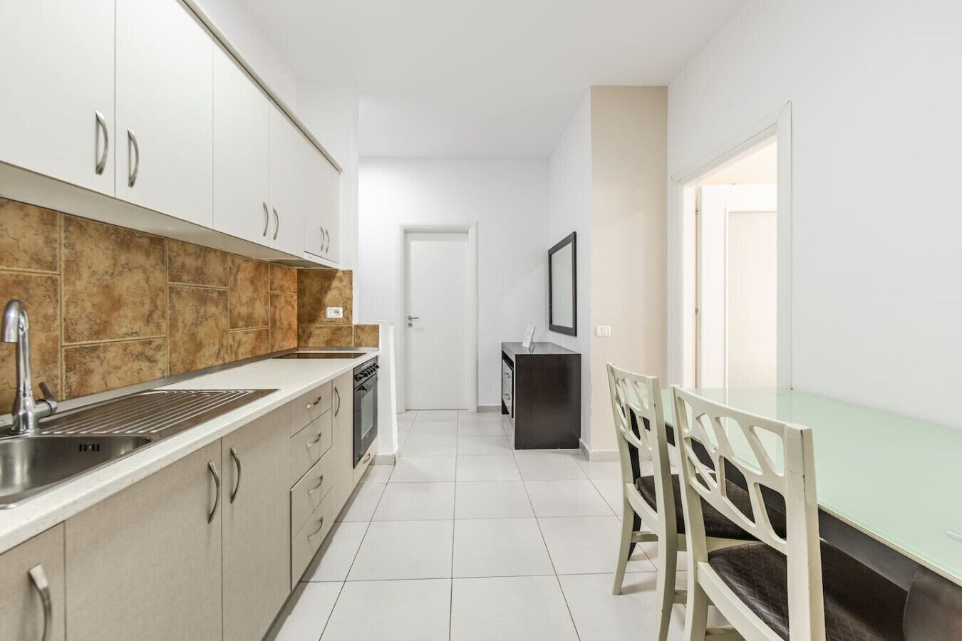 Een koelkast, een oven, een kookplaat, kookgerei, borden en bestek