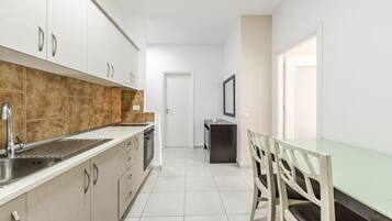 Een koelkast, een oven, een kookplaat, kookgerei, borden en bestek