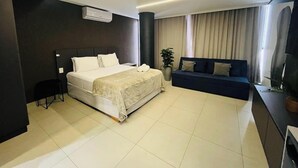 A modern hotel room with a large bed, a sofa, a TV, and a potted plant. - LM WAY TAMBAU (Joao Pessoa)
