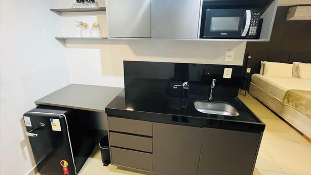A compact kitchen with a microwave, a small refrigerator, and a sink. - LM WAY TAMBAU (Joao Pessoa)