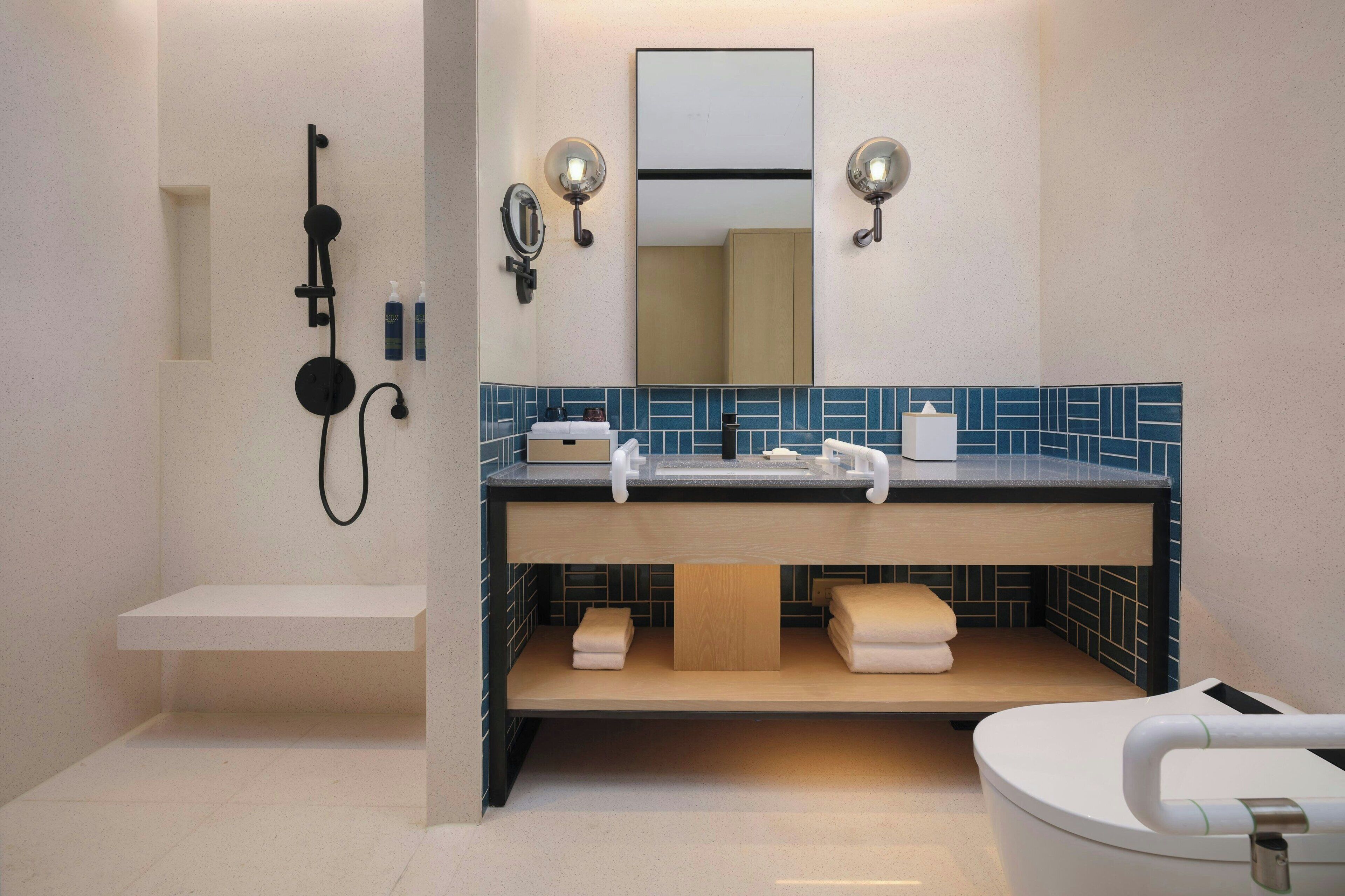 Une salle de bain moderne avec une douche, un lavabo avec un miroir et des toilettes.